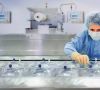 Pharmazeutische Mitarbeiterin in Schutzkleidung am Arbeitstisch