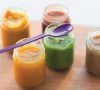 Bunte Smoothies in kleinen Gläschen mit lila Platiklöffel über einem Glas