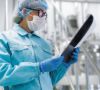 Mensch in Schutzkleidung mit Gerät in der Hand
