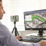 Mann vor Monitor mit Hand an der Maus und anderer Hand an der Tastatur